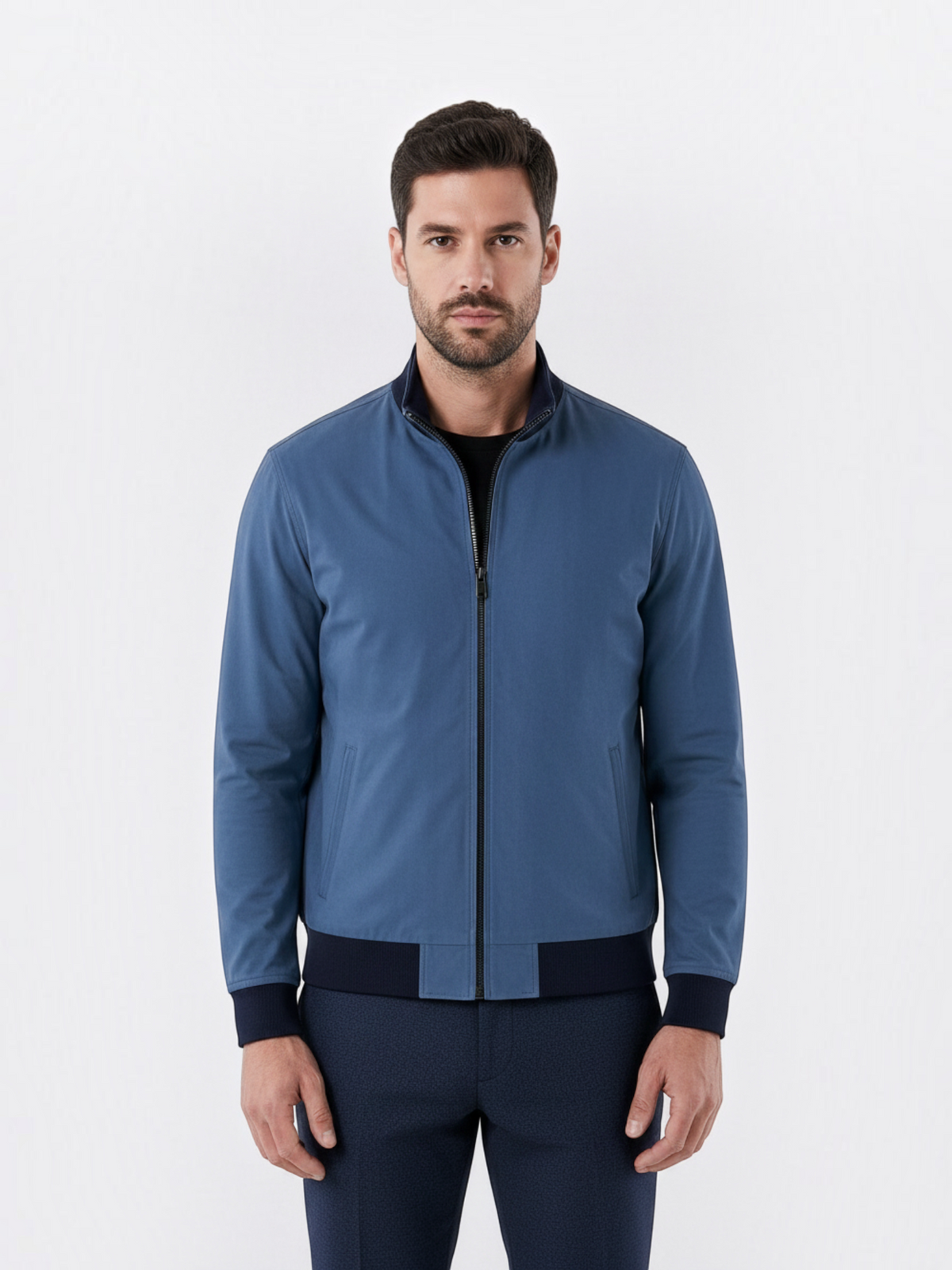 Homem vestindo jaqueta bomber azul Habitat Masculino com zíper frontal, gola banda e punhos em ribana preta.