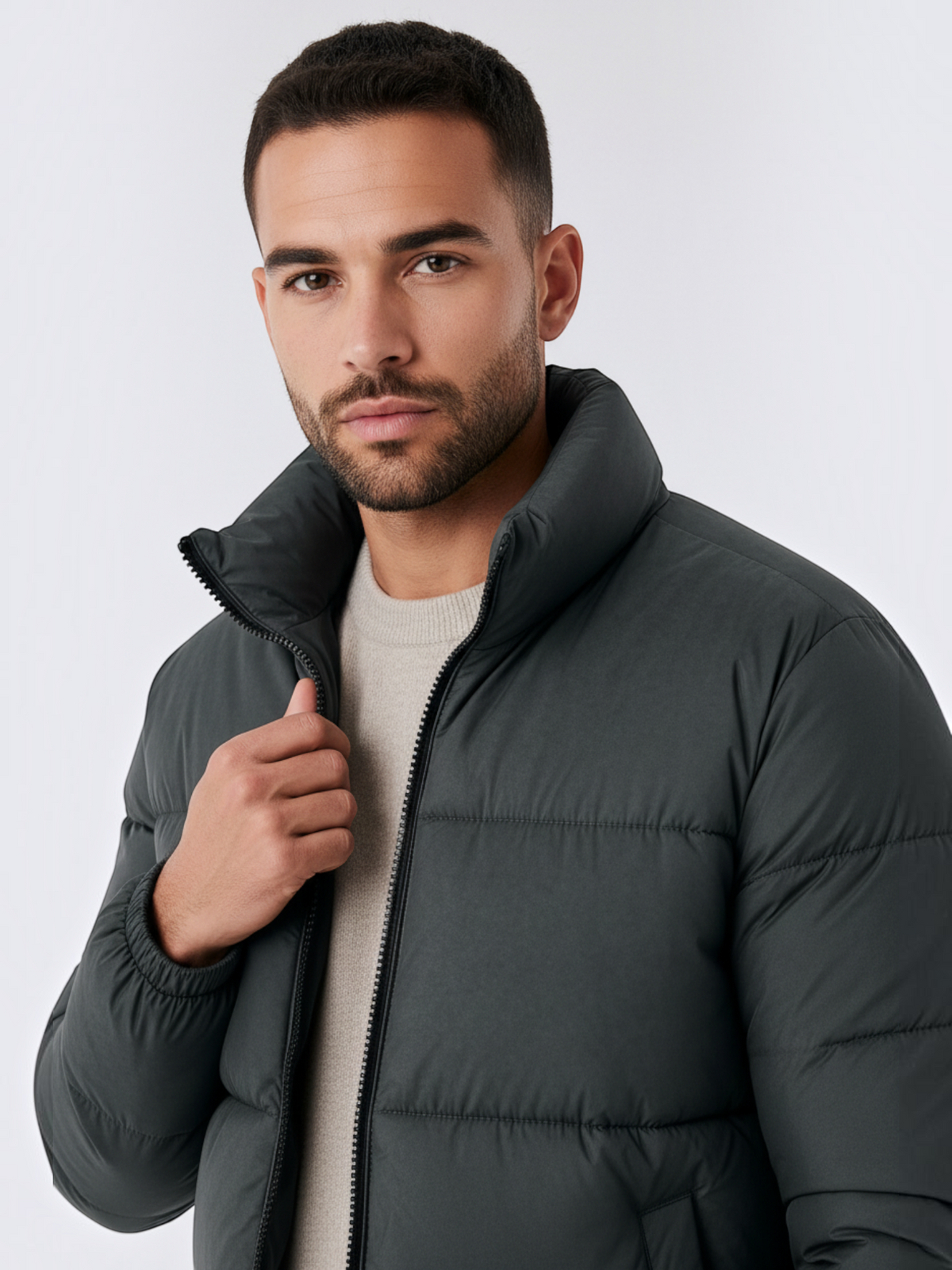 Homem vestindo jaqueta puffer cinza Habitat Masculino com gola alta e zíper frontal sobre malha de tom neutro.