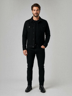 Modelo vestindo jaqueta jeans preta slim Habitat Masculino com bolsos no peito, calça preta e botas em fundo cinza.