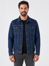 Homem vestindo jaqueta jeans azul Habitat Masculino estilo trucker com bolsos no peito e botões bronzeados.