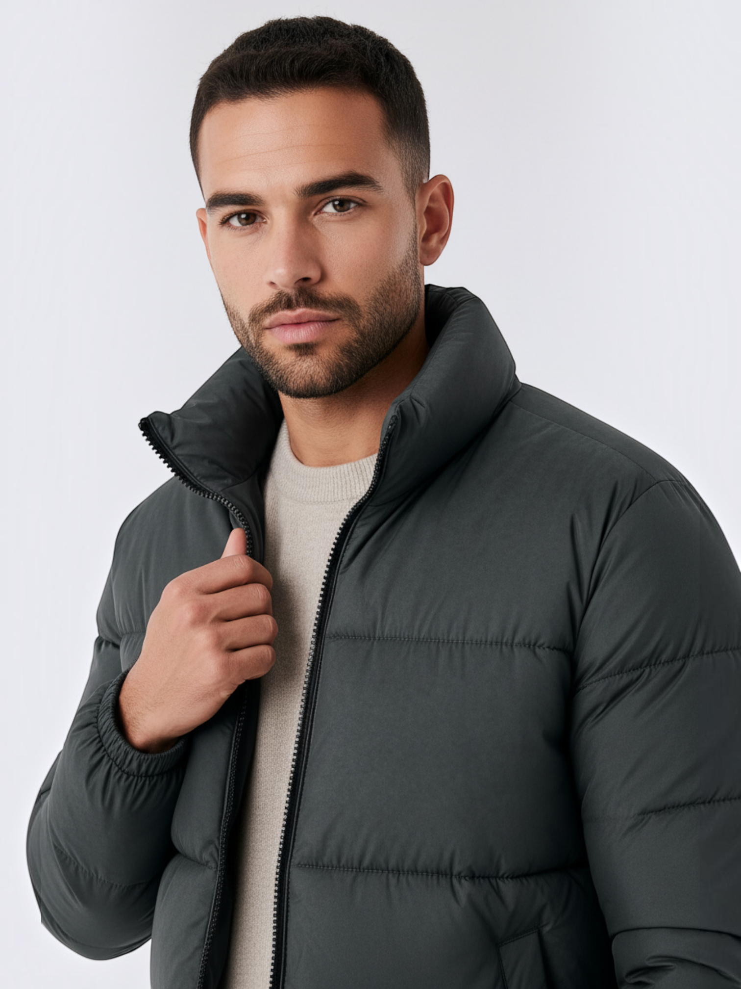 Homem vestindo jaqueta puffer cinza Habitat Masculino com gola alta e zíper frontal sobre malha de tom neutro.