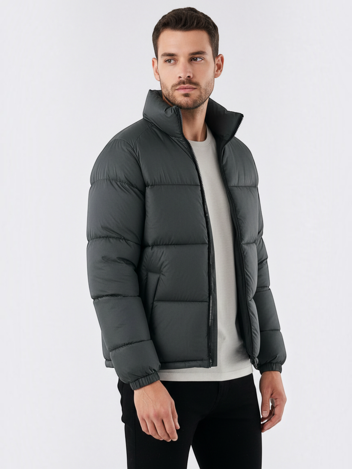 Homem vestindo jaqueta puffer cinza escuro Habitat Masculino com gola alta, zíper frontal e bolsos impermeáveis.