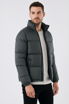 Homem vestindo jaqueta puffer cinza escuro Habitat Masculino com gola alta, zíper frontal e bolsos impermeáveis.