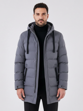 Jaqueta puffer longa cinza Habitat Masculino com capuz, zíper frontal e bolsos laterais, vestida por modelo masculino.
