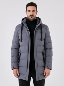 Jaqueta puffer longa cinza Habitat Masculino com capuz, zíper frontal e bolsos laterais, vestida por modelo masculino.