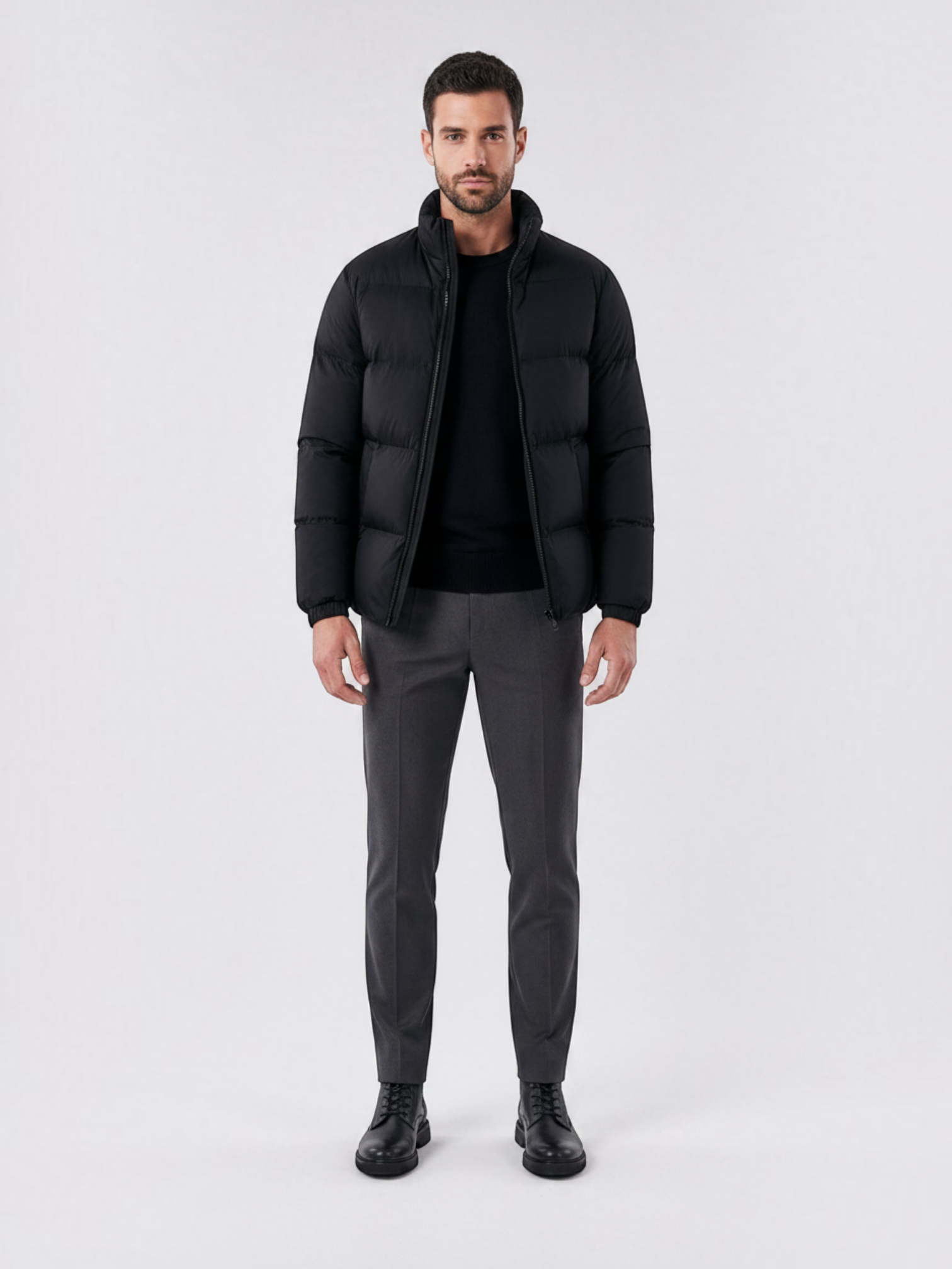 Modelo vestindo jaqueta puffer preta Habitat Masculino com gola alta, zíper e forro impermeável em fundo neutro.