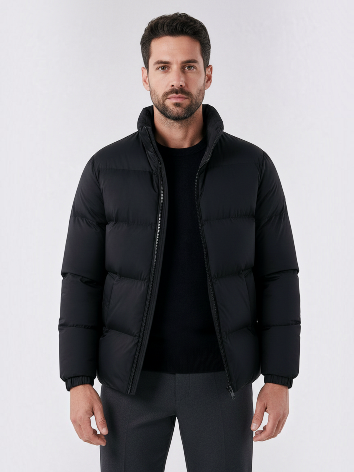 Homem vestindo jaqueta puffer preta Habitat Masculino com gola alta e fechamento em zíper sobre blusa de malha