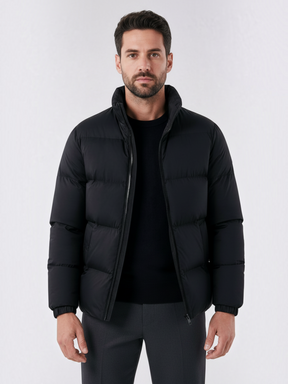 Homem vestindo jaqueta puffer preta Habitat Masculino com gola alta e fechamento em zíper sobre blusa de malha