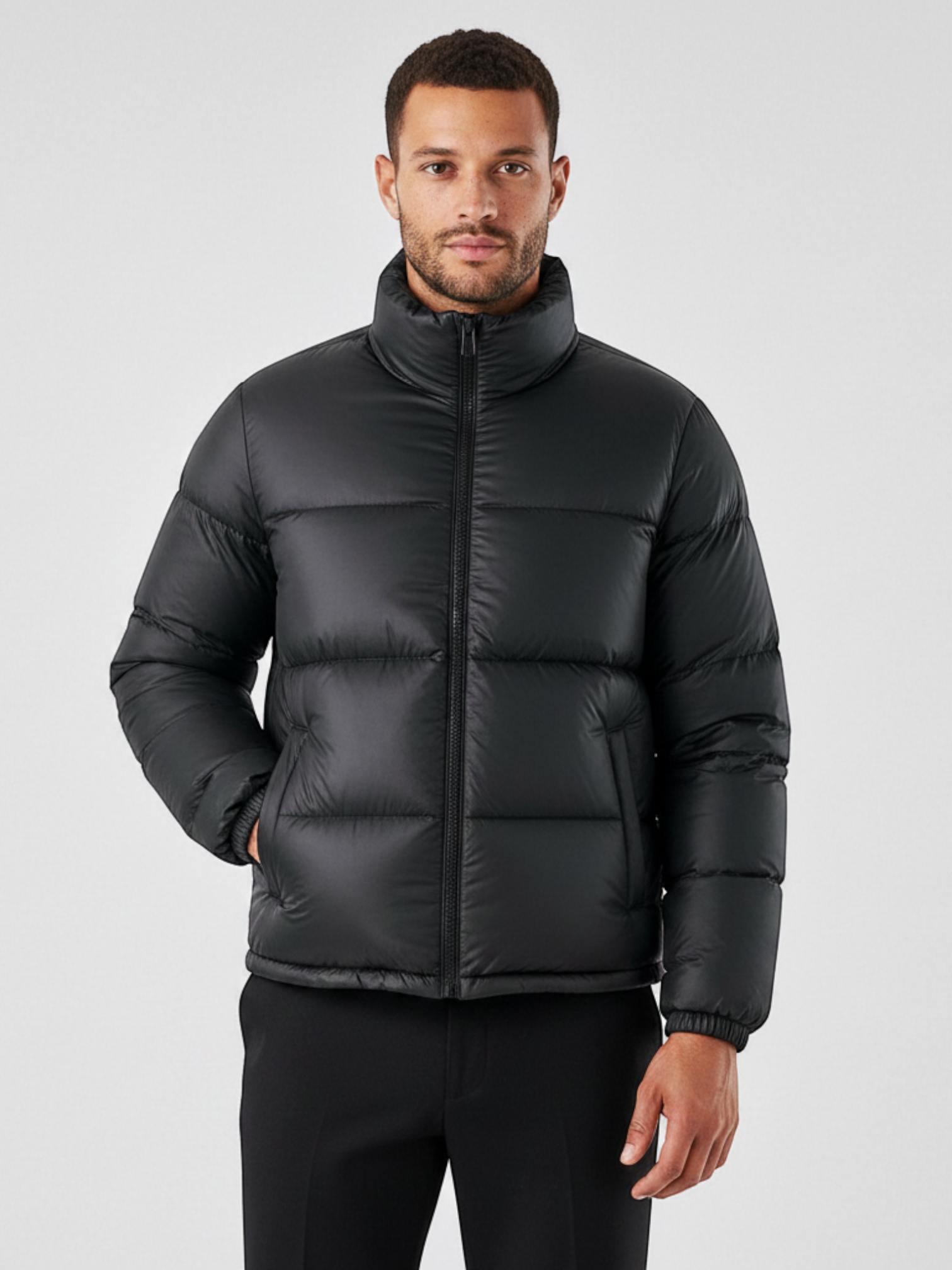 Modelo vestindo jaqueta puffer preta Habitat Masculino com gola alta, zíper frontal e bolsos impermeáveis.