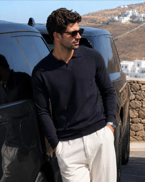 Homem vestindo suéter azul marinho Habitat Masculino com gola polo, encostado em carro preto em ambiente externo.