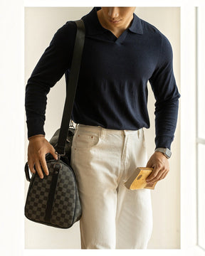 Homem vestindo suéter azul marinho Habitat Masculino com gola polo, calça branca e bolsa de ombro xadrez